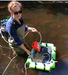 catherine is standing in water with a floating contraption of wires