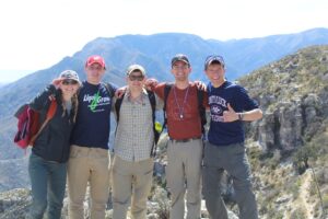five students pose happily in front of a mountain
