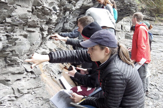 Students studying a rocky outcropping.